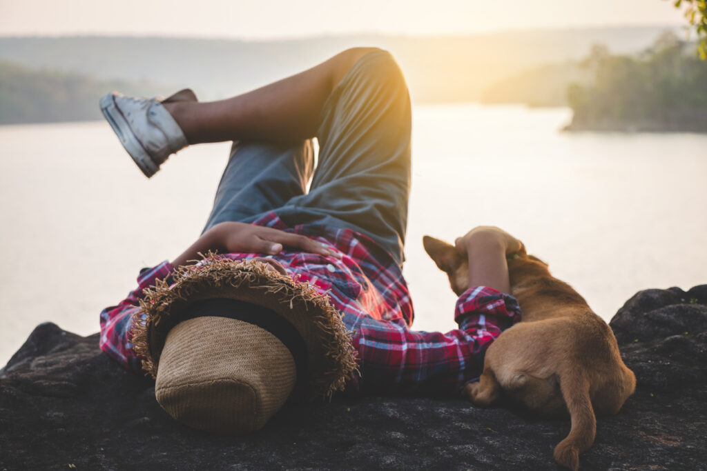 man with a dog next to a lake