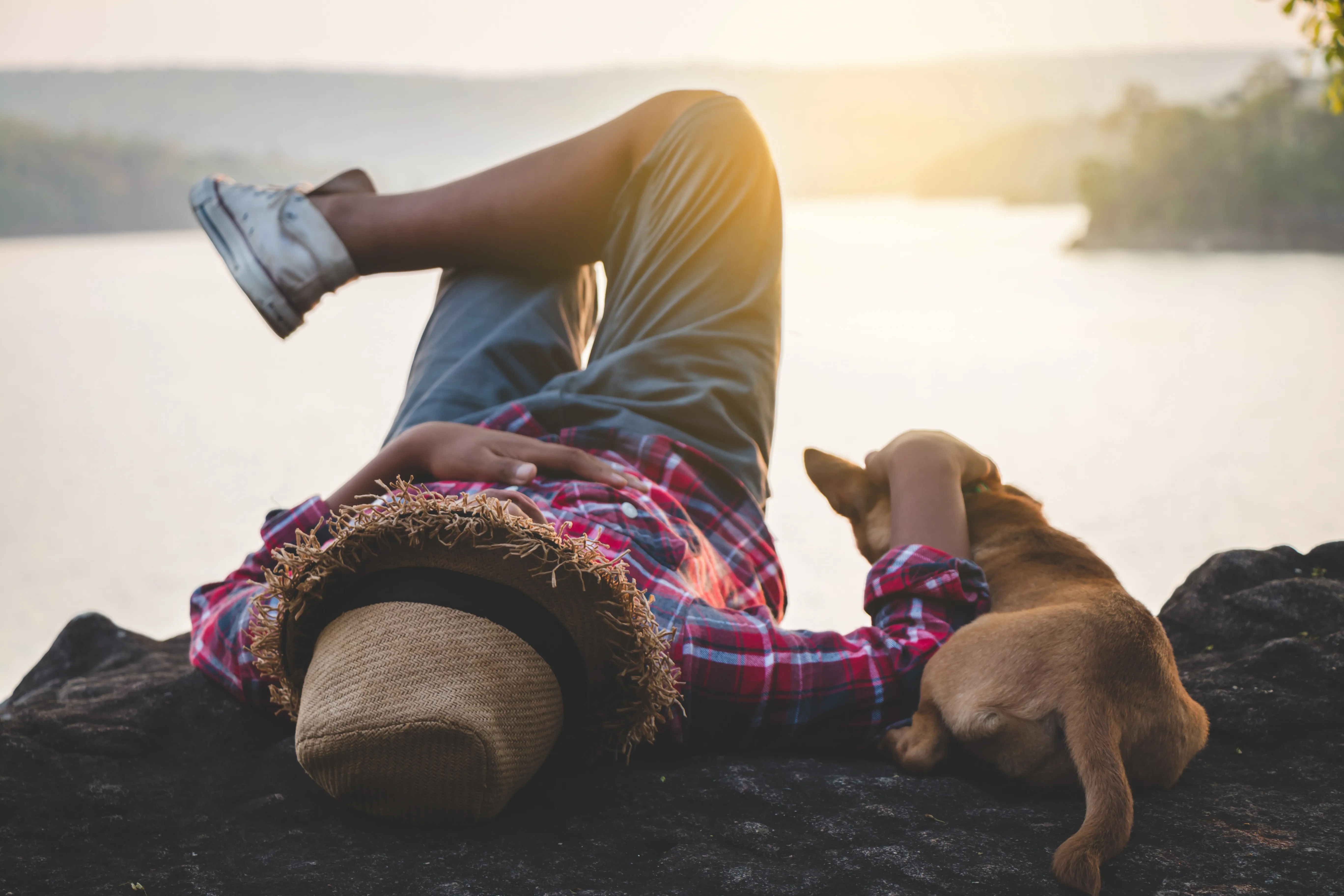 man with a dog next to a lake